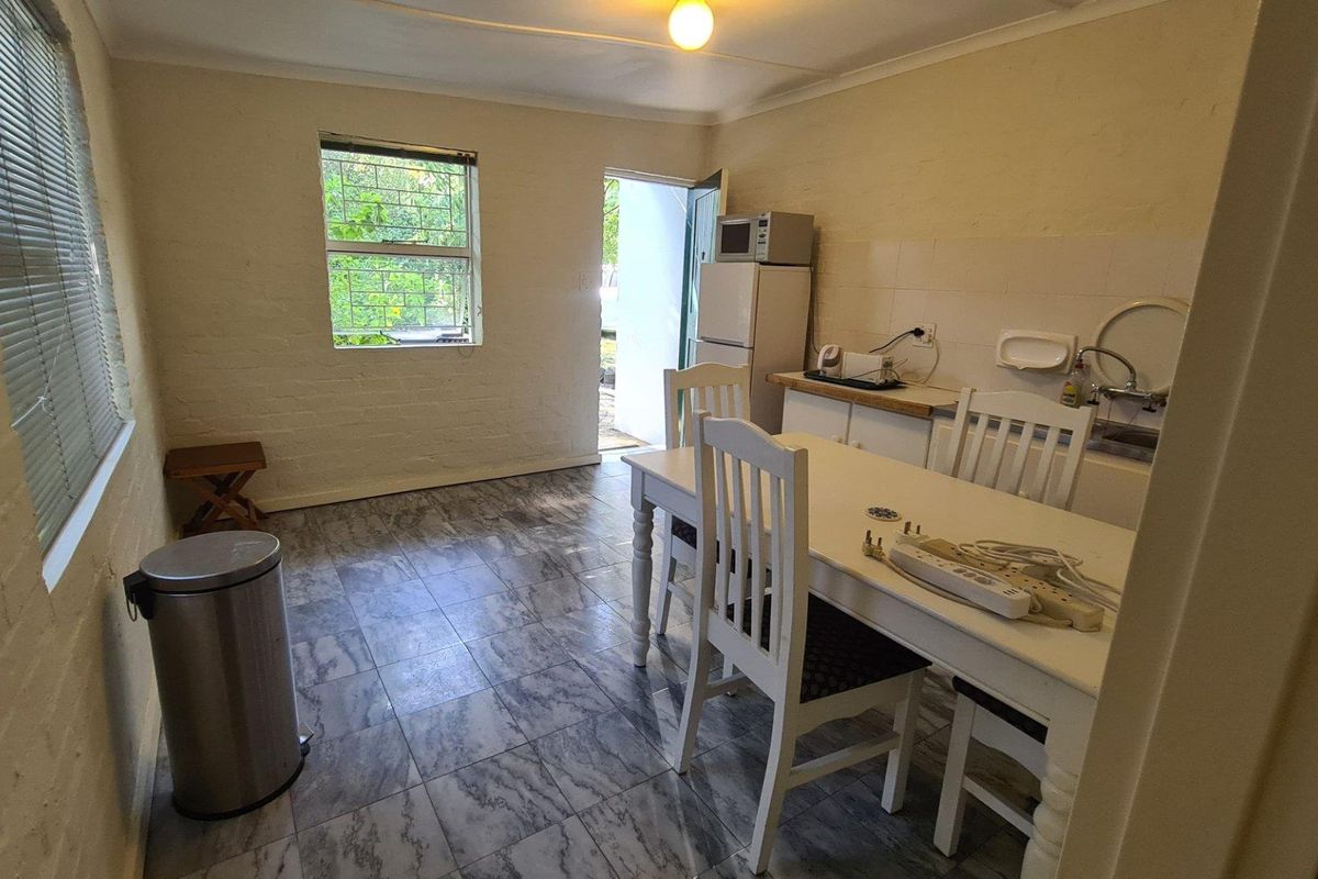 A functional kitchen area featuring tiled flooring, a sink, and direct access to the exterior, offering potential for modernization and aesthetic improvement.