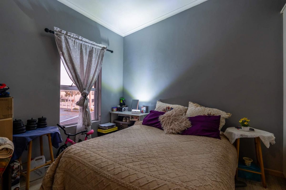 A bedroom featuring grey walls, a window with curtain, and neutral flooring.