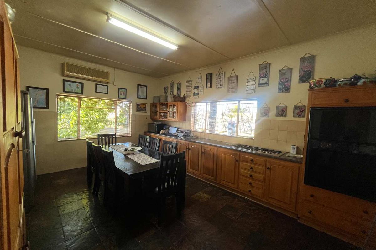 A spacious kitchen featuring wooden cabinetry, a built-in gas hob, and dark stone flooring, offering a functional layout with ample natural light.