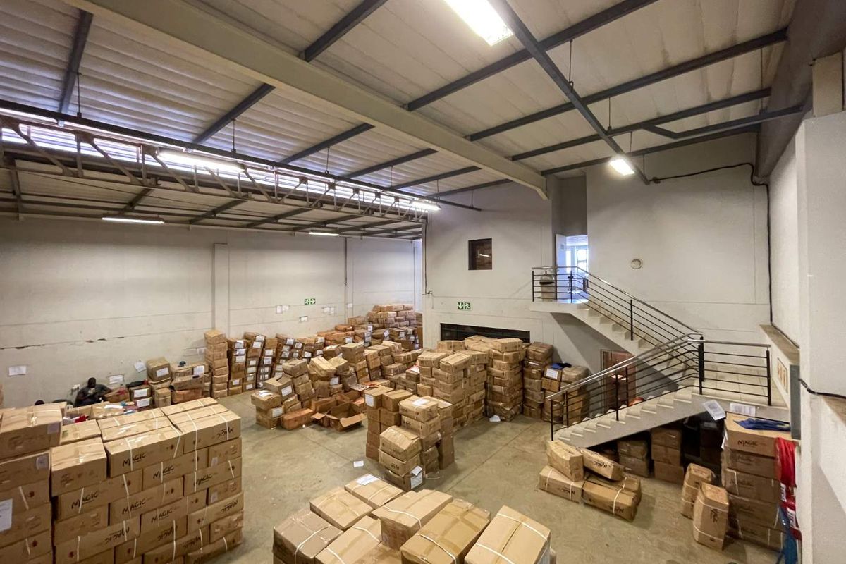 Spacious industrial utility or warehouse area featuring high ceilings with exposed steel trusses, concrete flooring, and an internal staircase leading to an upper level.