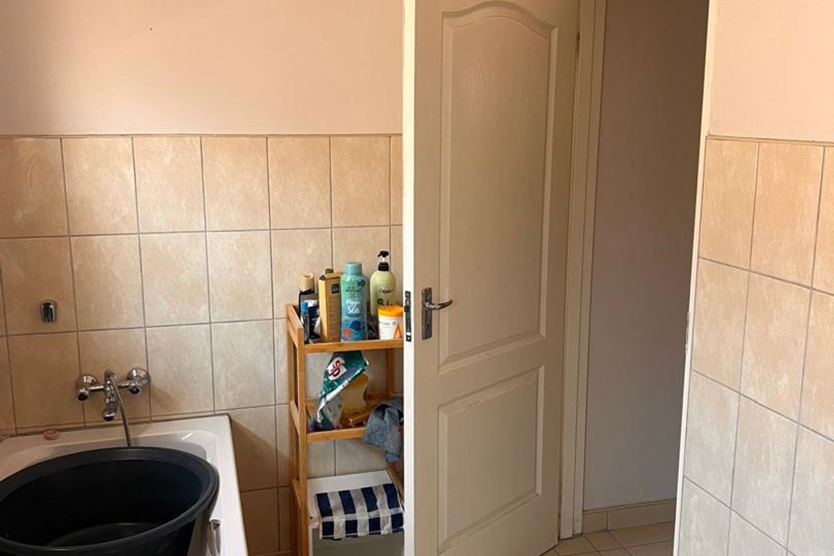A functional bathroom featuring a bathtub with wall-mounted mixer tap, tiled walls, and tiled flooring, providing a practical space for daily use.