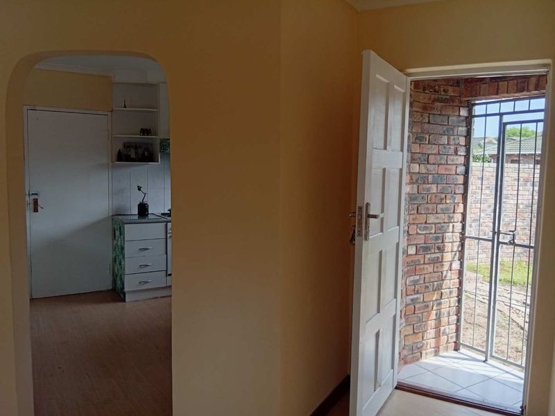 An entry area featuring an arched doorway leading to a kitchen, with a security gate and tiled threshold at the main entrance.