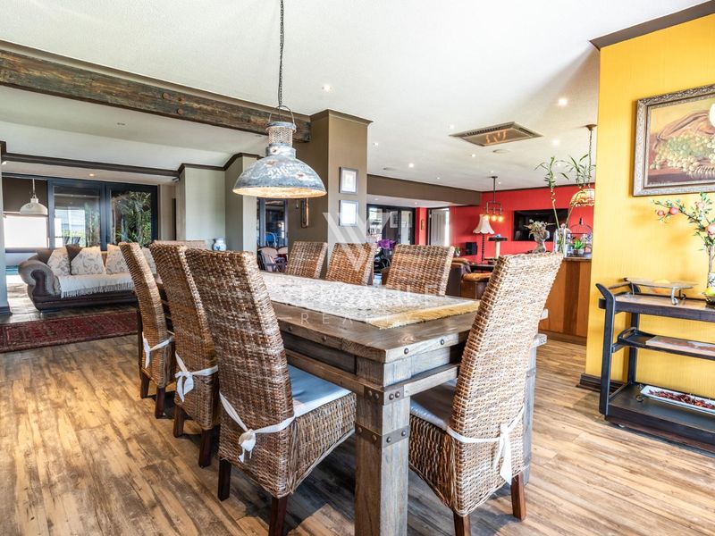 Spacious open-plan living and dining area featuring exposed timber beams, recessed lighting, and durable laminate flooring, creating a warm and inviting atmosphere.