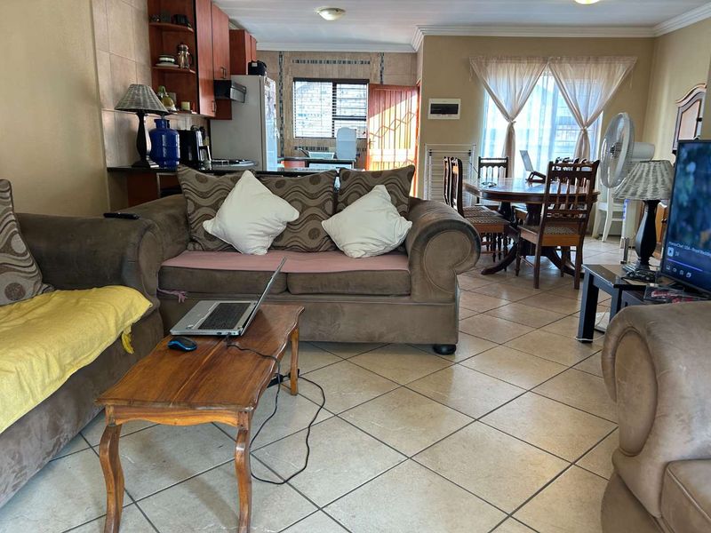 Open-plan living and dining area featuring tiled flooring and an integrated kitchen with wooden cabinetry, providing a functional and connected living space.