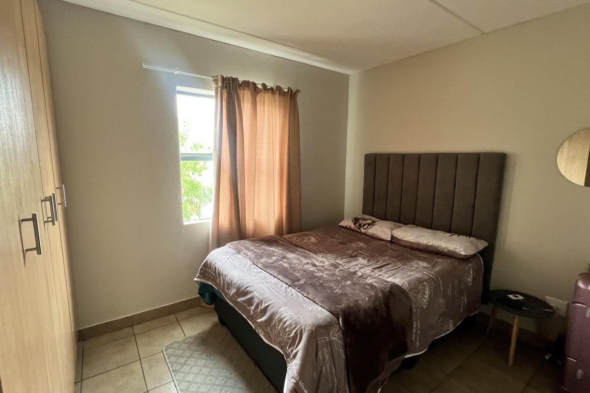 A functional bedroom featuring tiled flooring and a built-in wardrobe, providing essential storage space and a neutral foundation for interior design.