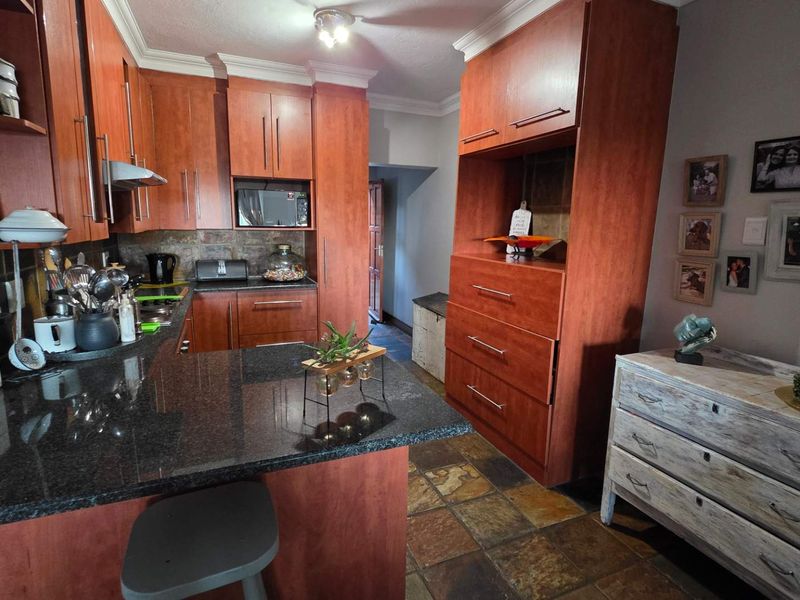 A functional kitchen featuring warm-toned wooden cabinetry, dark granite countertops, and durable stone tile flooring, offering ample storage and workspace.