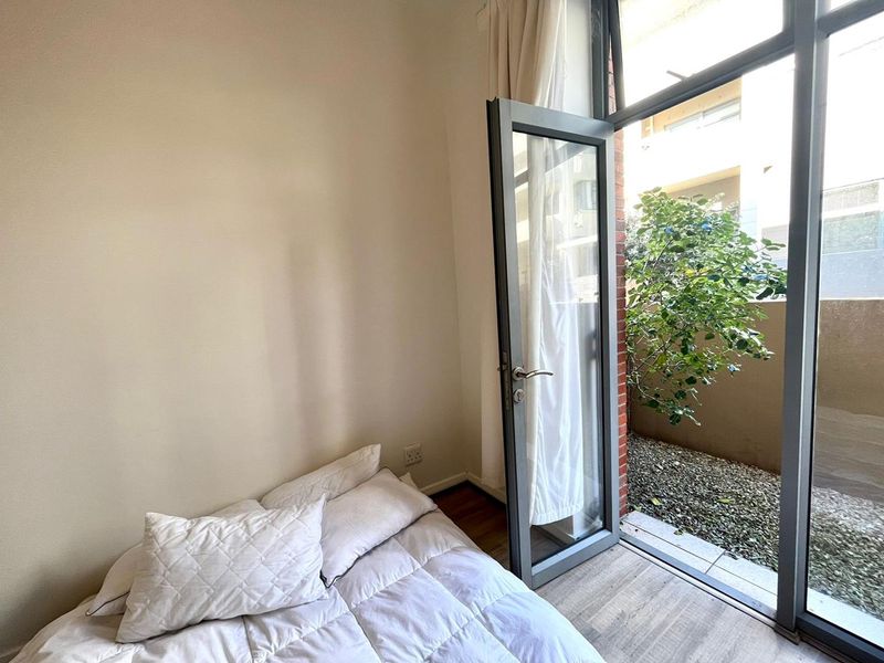 Bedroom featuring laminate flooring and a large aluminium framed glass door providing direct access to a private outdoor area.