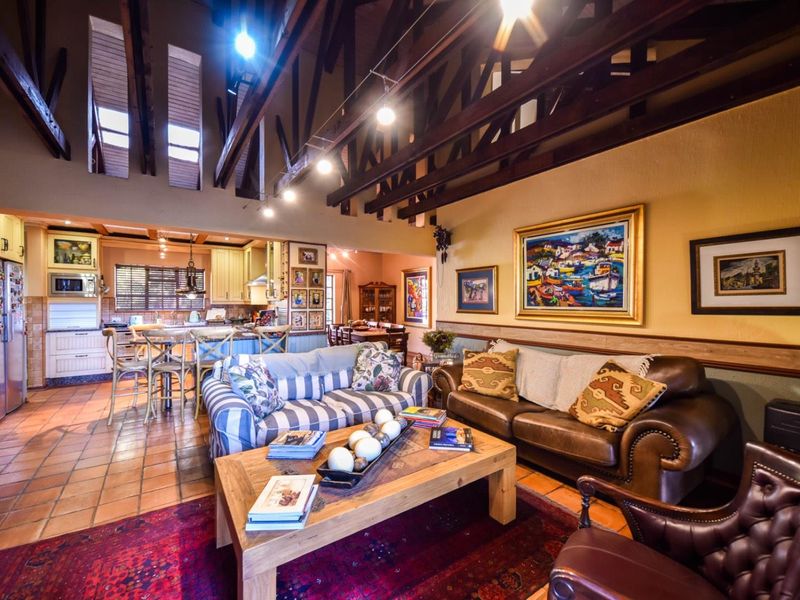 Spacious open-plan living area featuring high vaulted ceilings with exposed timber trusses, terracotta flooring, and a well-integrated kitchen with island seating.