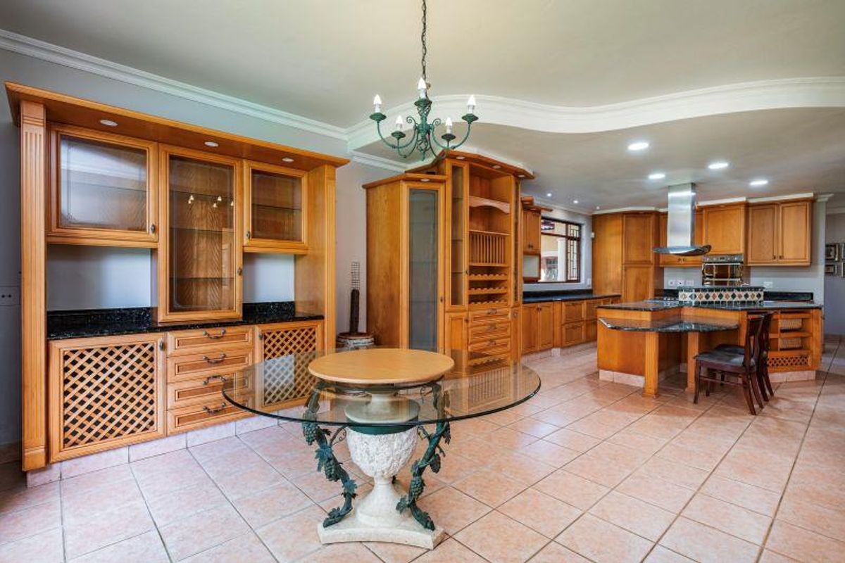 Spacious kitchen featuring extensive timber cabinetry, granite countertops, a central island with breakfast bar, and integrated stainless steel extractor fan.