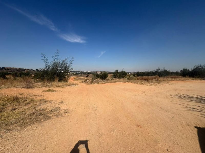 An expansive view of an undeveloped industrial plot featuring natural terrain and open land.