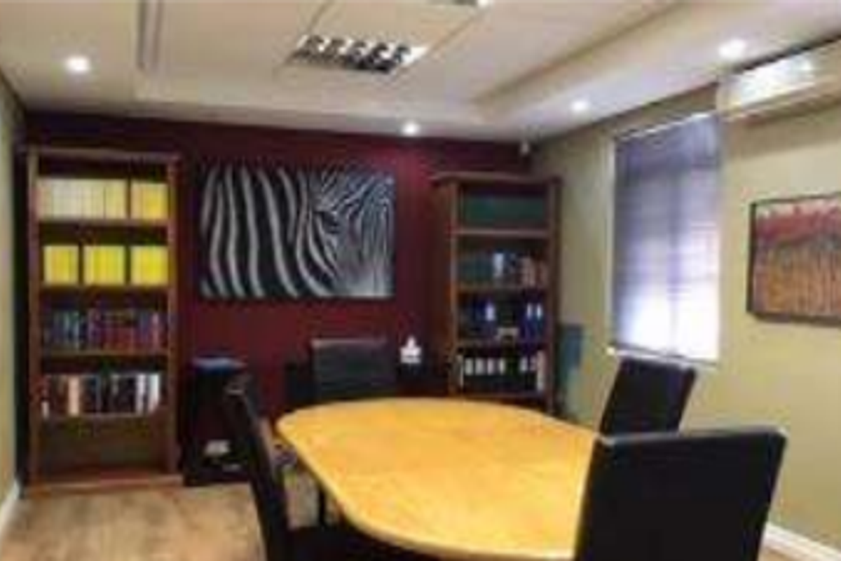 A professional office space featuring recessed ceiling lighting, an integrated air conditioning unit, and laminate flooring.
