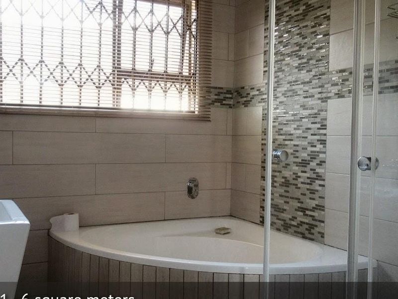 Modern bathroom featuring a corner bathtub, glass-enclosed shower, and decorative mosaic tile accents.