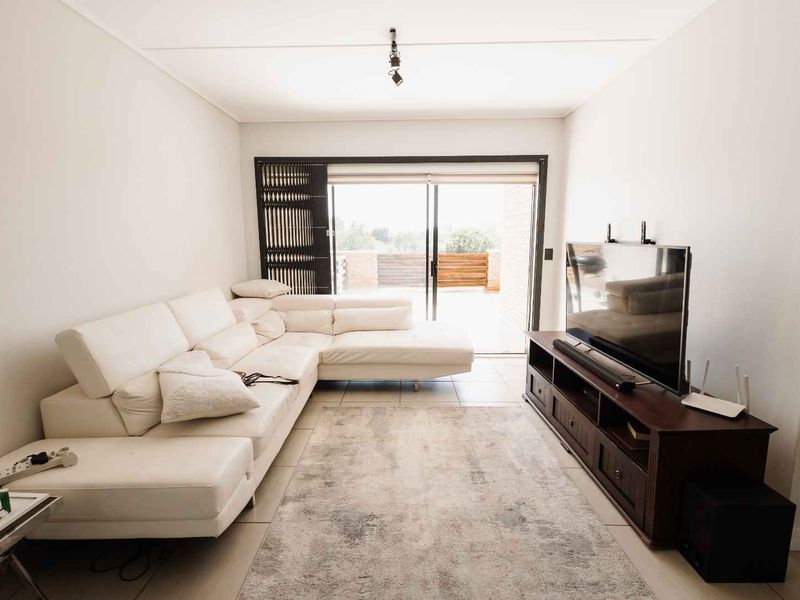 A bright and well-maintained living room featuring tiled flooring and large sliding glass doors that provide access to an outdoor area.