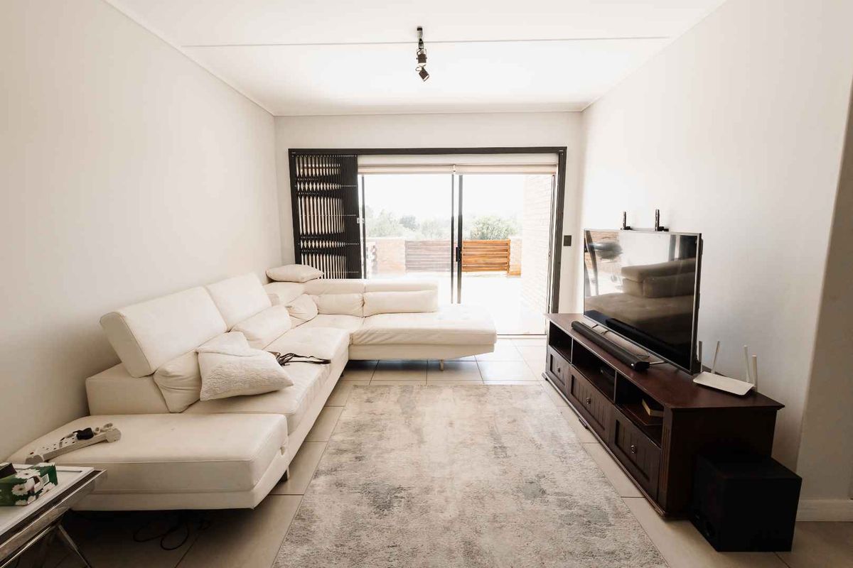 A bright and well-maintained living room featuring tiled flooring and large sliding glass doors that provide access to an outdoor area.