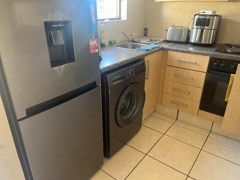 A functional kitchen featuring laminate cabinetry, a stainless steel sink, built-in oven, and tiled flooring, offering a practical layout for daily use.