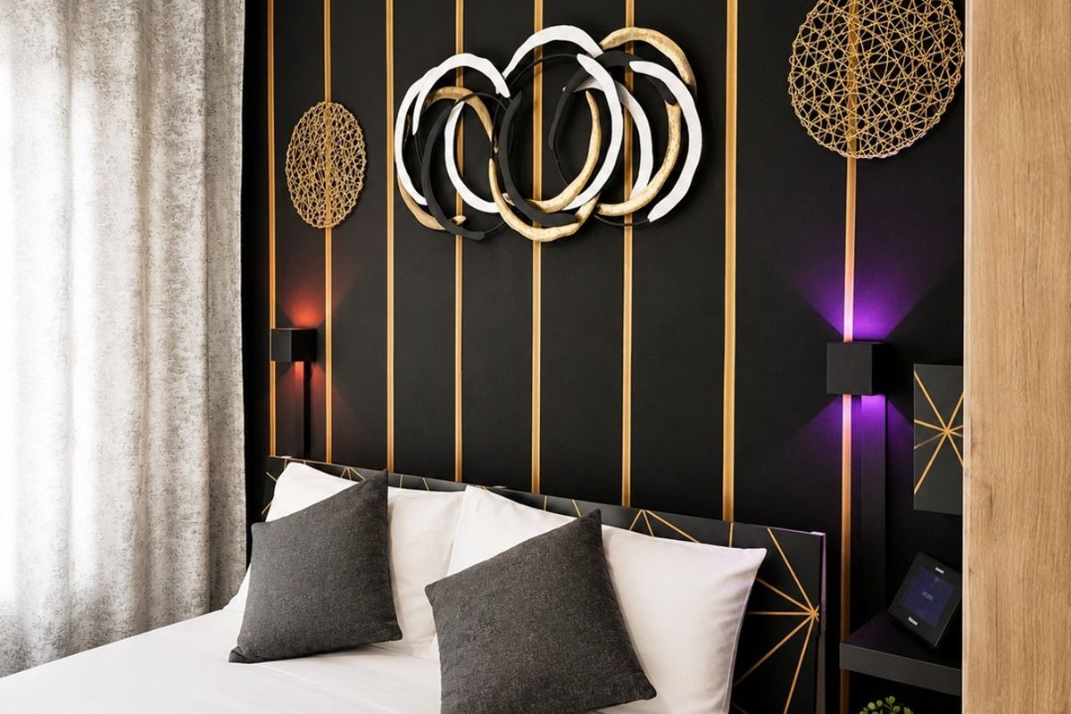 A modern bedroom featuring a stylish black and gold accent wall with integrated lighting and built-in bedside shelving.