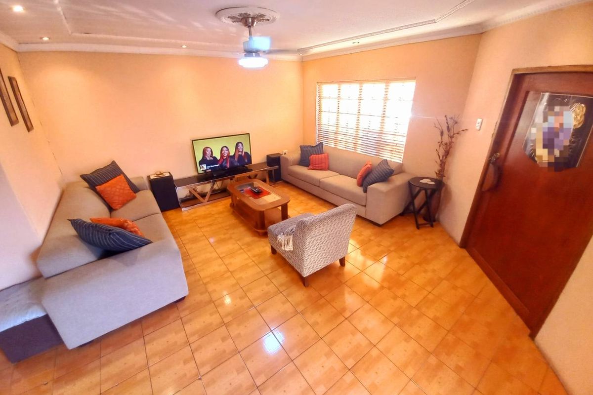 A comfortable living room featuring tiled flooring, recessed ceiling lighting, and a ceiling fan, providing a functional space for relaxation.