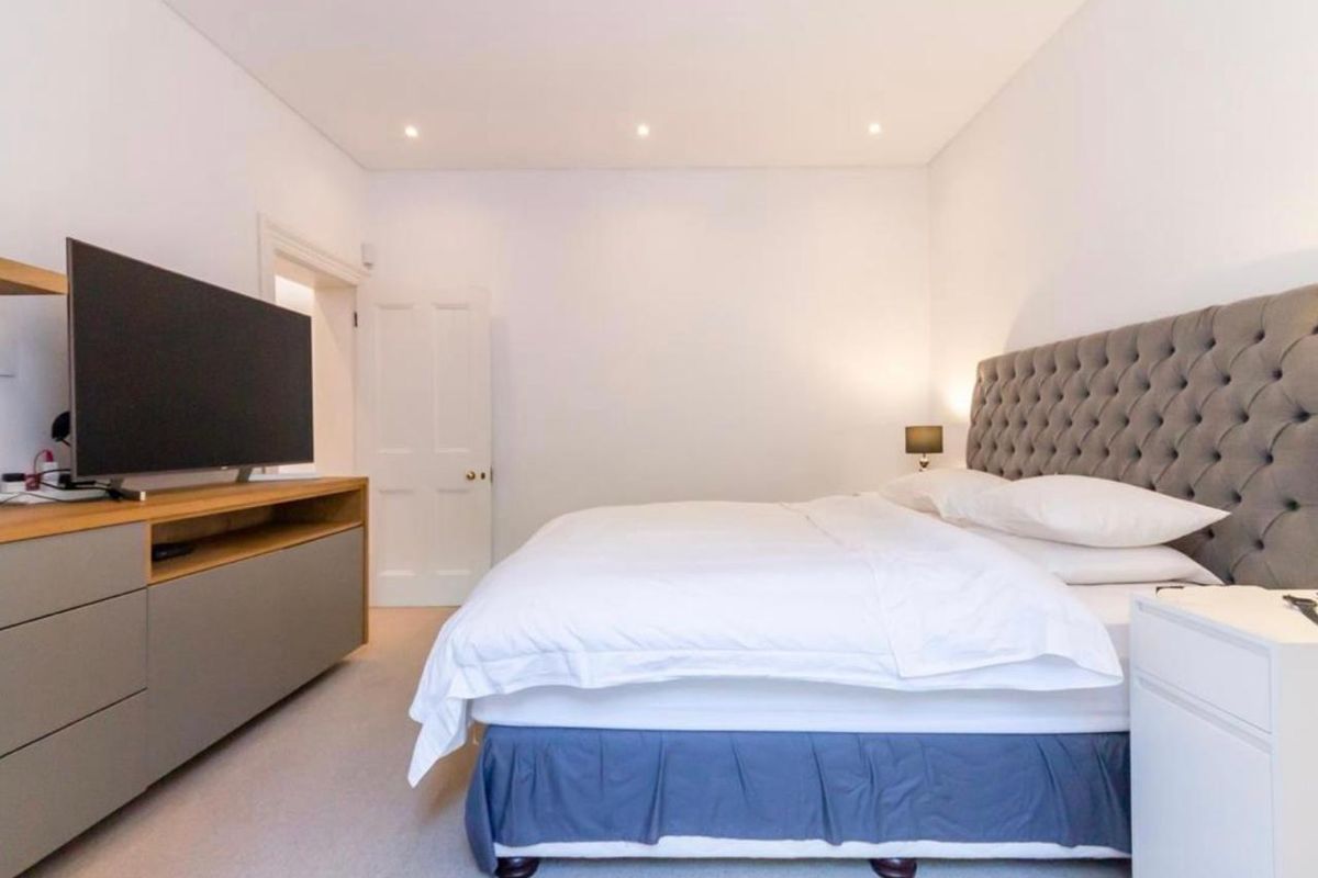 A well-maintained bedroom featuring neutral walls, recessed downlighting, and fitted carpeting, providing a clean and comfortable living space.