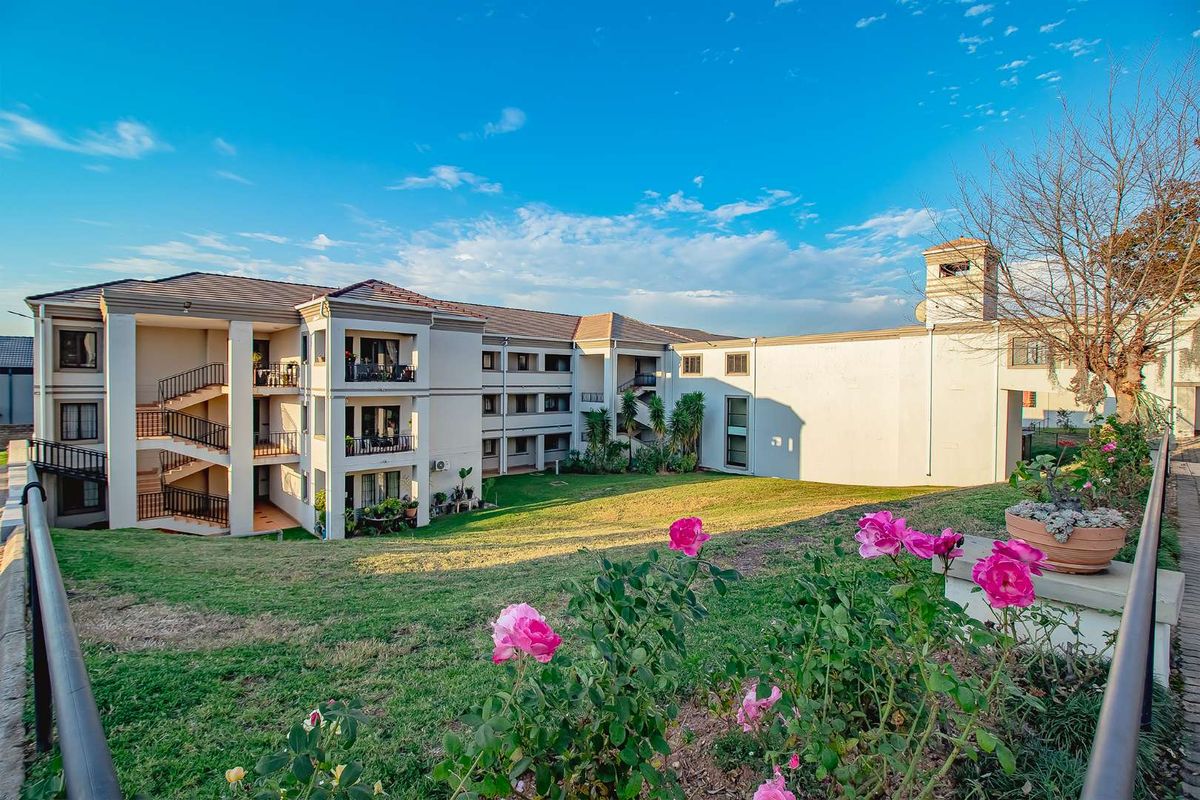 A view of the retirement village complex featuring multi-level residential units with balconies, set within landscaped grounds and green spaces.