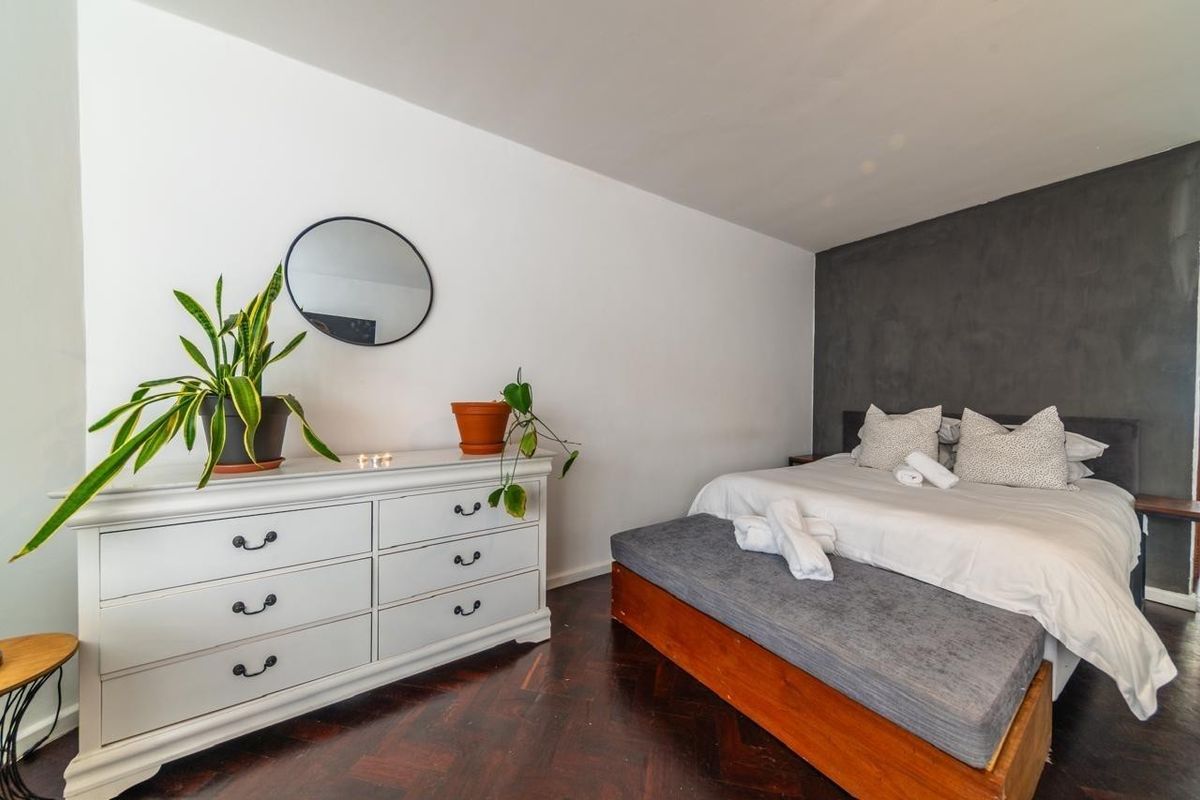 A well-maintained bedroom featuring dark herringbone timber flooring and a contrasting dark grey feature wall behind the bed area.