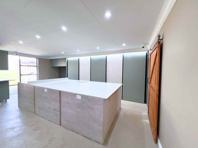 Modern kitchen featuring a large central island with stone countertop, sleek built-in cabinetry, recessed lighting, and a rustic sliding barn door.