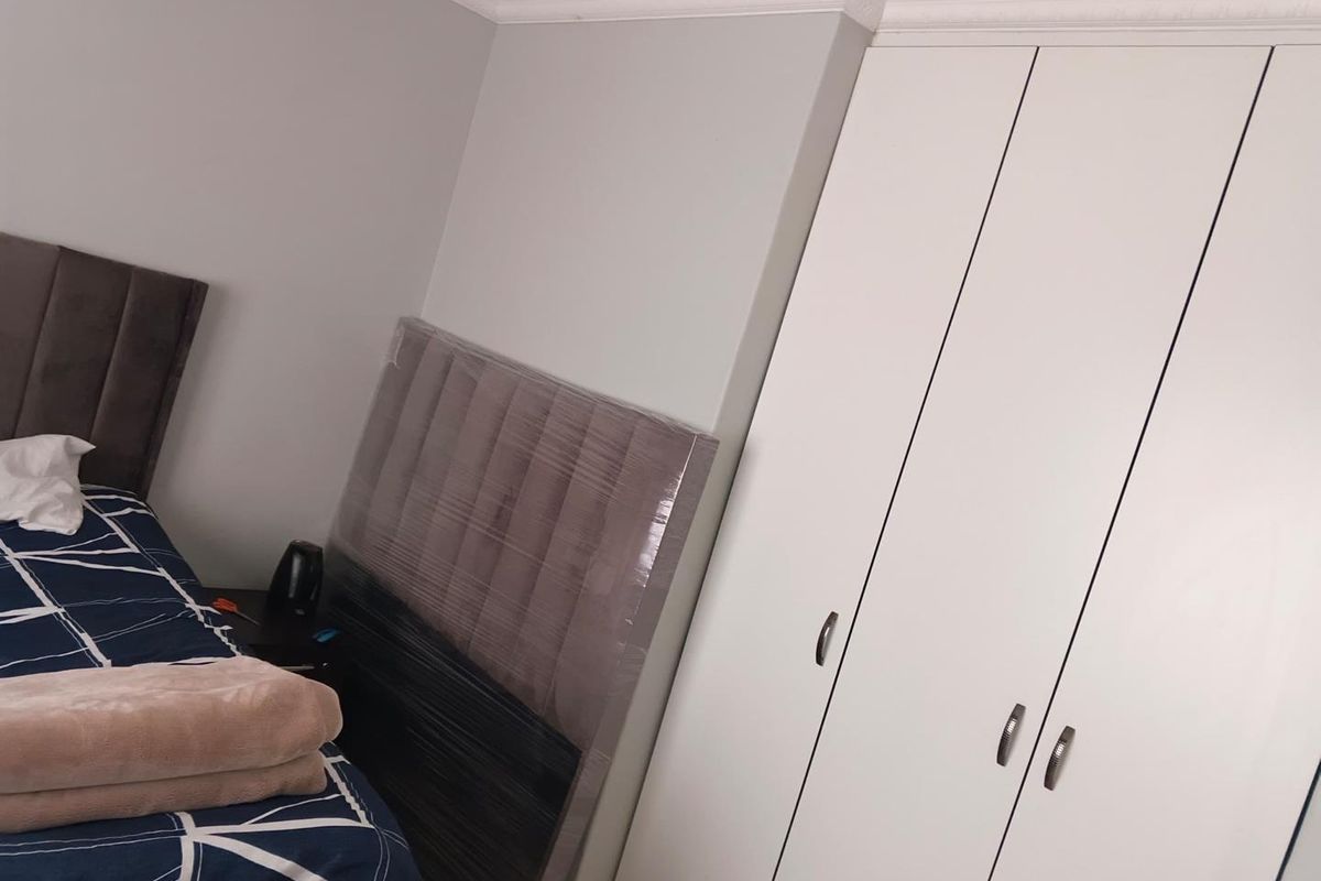 A bedroom featuring a built-in wardrobe with white doors and decorative crown molding.