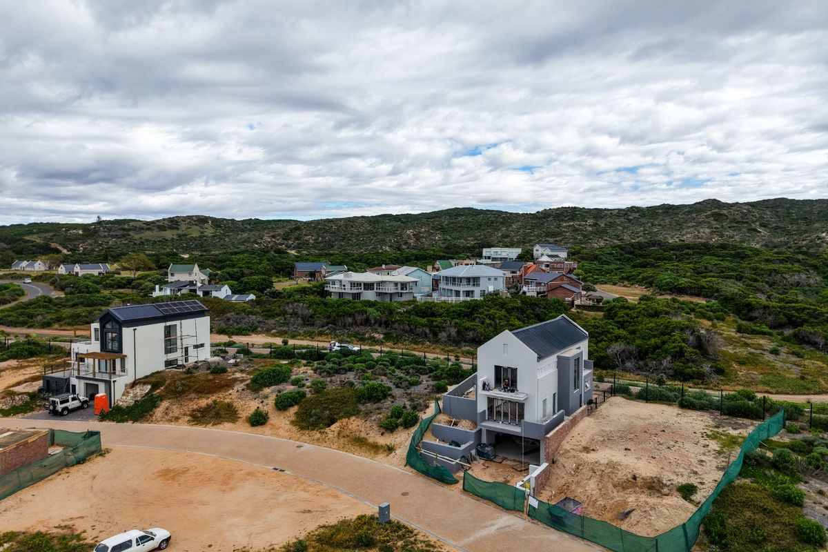Aerial view of a coastal residential estate featuring modern homes with metal roofing and solar panels under construction.
