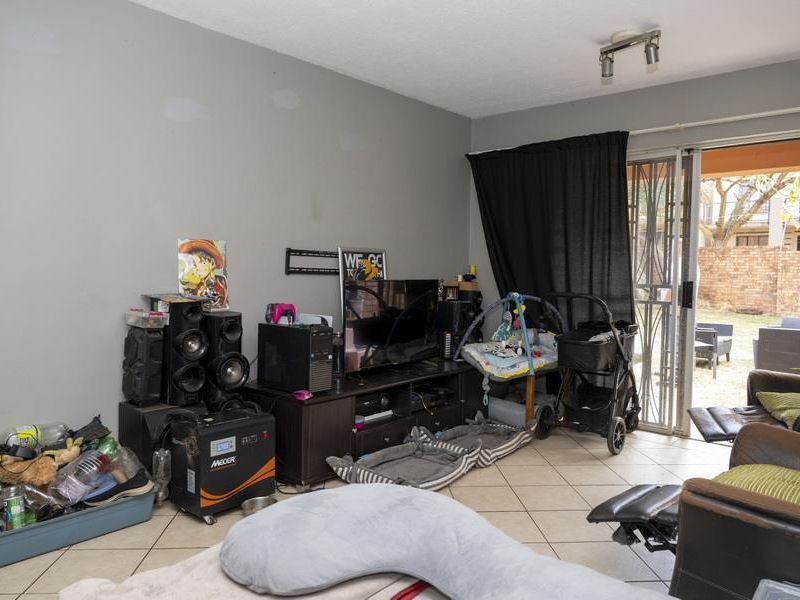 A living room featuring tiled flooring and sliding glass doors that provide access to an outdoor patio area.