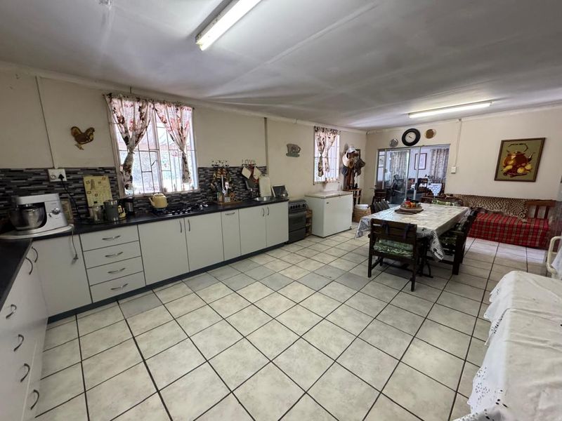 Spacious open-plan kitchen and dining area featuring tiled flooring, built-in cabinetry, and a gas hob, offering a functional layout for family living.