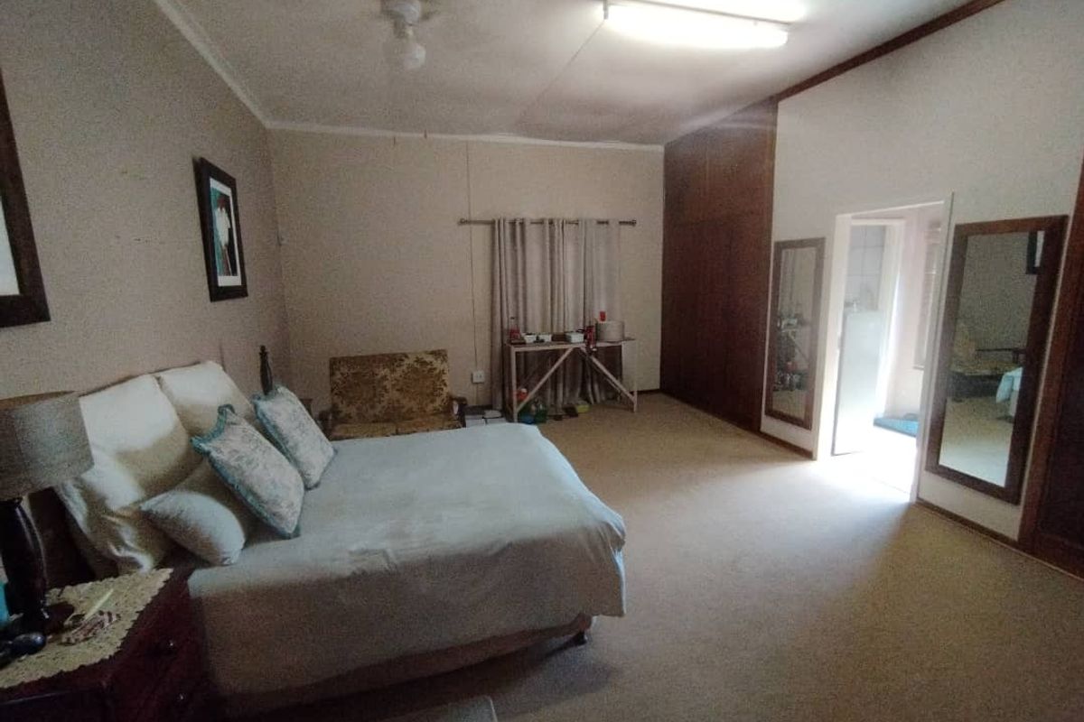 Spacious bedroom featuring built-in wooden cabinetry, neutral carpeting, and direct access to an adjoining bathroom area.