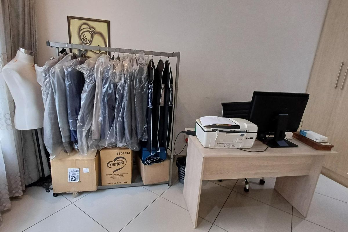 A bedroom featuring tiled flooring and a built-in wardrobe, currently utilized as a home office and storage space.