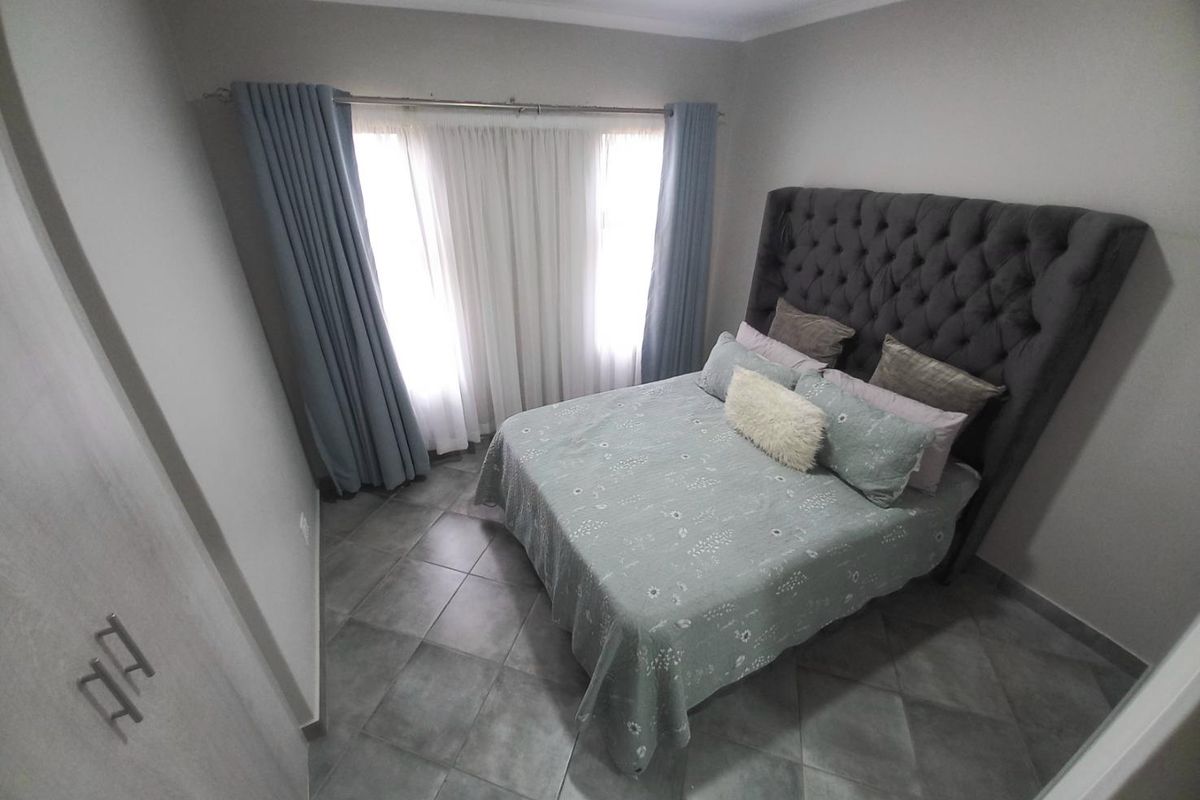 A well-maintained bedroom featuring neutral wall tones, tiled flooring, and built-in cabinetry, offering a clean and functional living space.