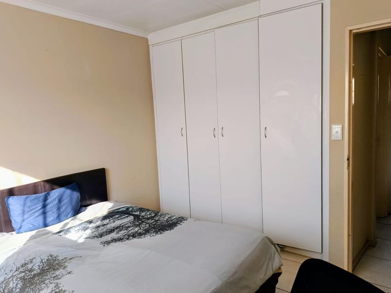 A bedroom featuring built-in cupboards with white doors and neutral wall finishes.