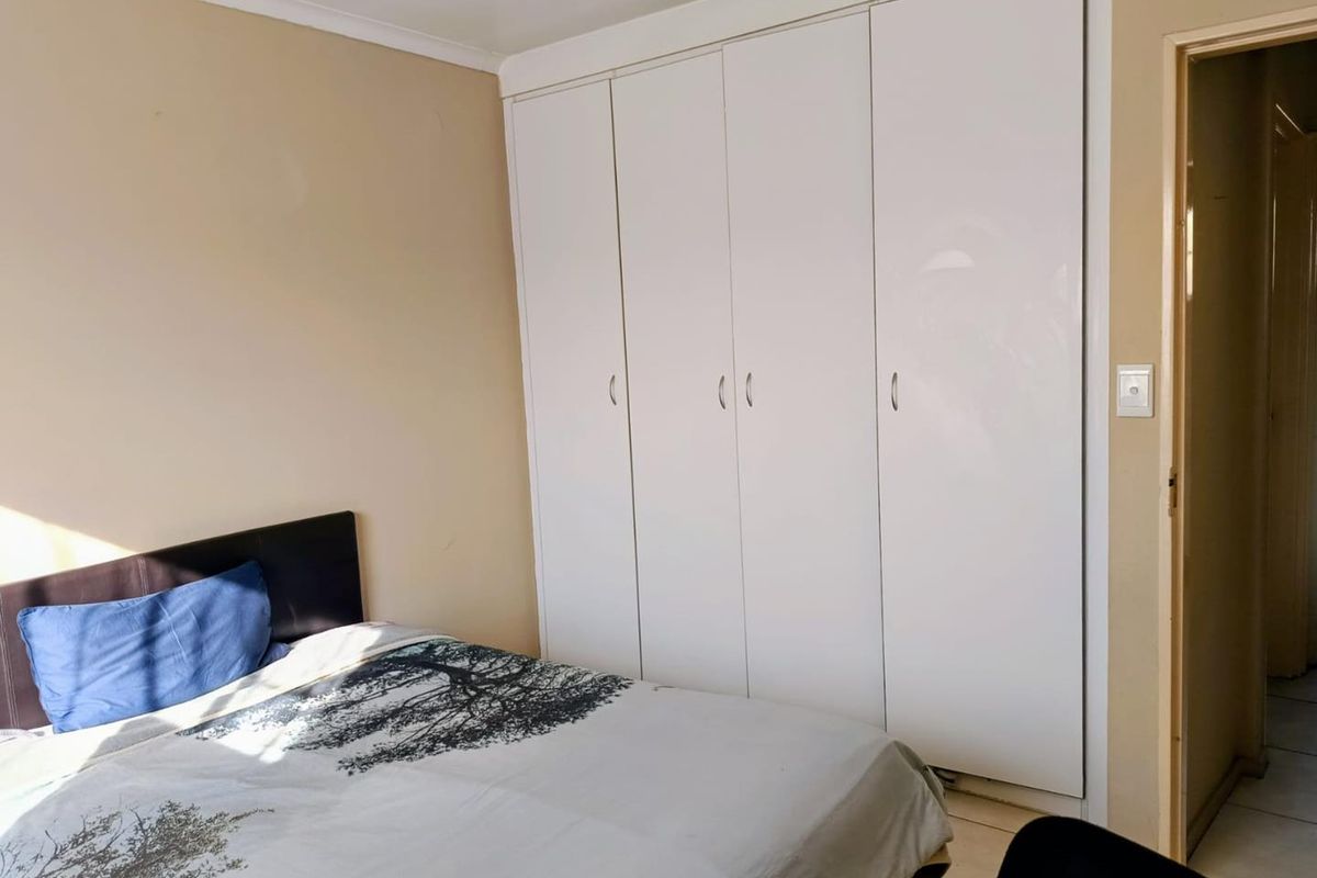 A bedroom featuring built-in cupboards with white doors and neutral wall finishes.