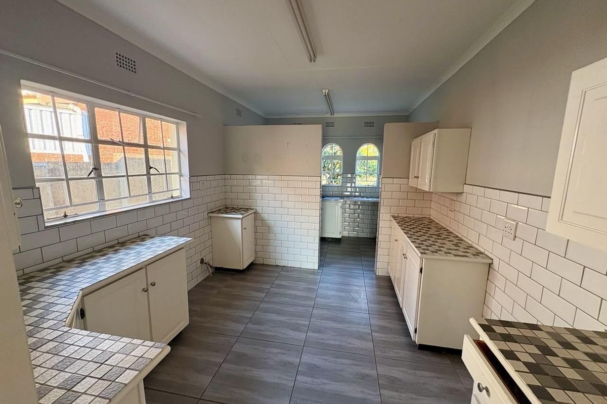 A spacious, empty kitchen featuring subway tile backsplashes, tiled countertops, and neutral floor tiles, offering a functional layout ready for modernization.