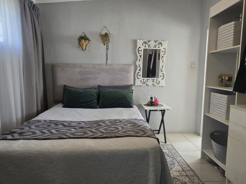A cozy bedroom featuring tiled flooring and a built-in shelving unit, offering a functional and well-maintained living space.