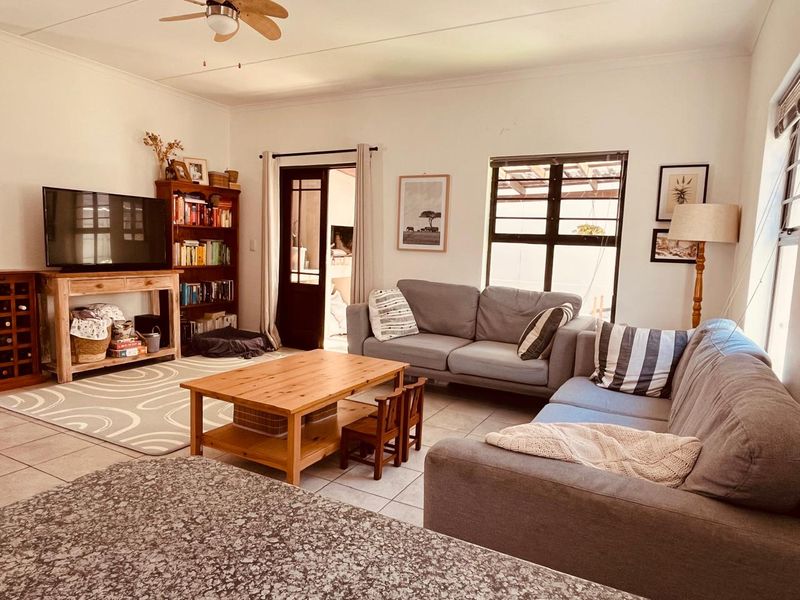 A comfortable living room featuring tiled flooring, a ceiling fan, and a glass-paneled door leading to an adjacent space.
