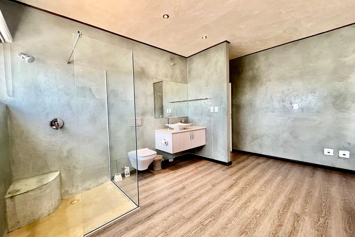 Modern bathroom featuring a walk-in shower with glass screen, wall-hung toilet, and a contemporary vanity with vessel sink, finished with polished concrete-style walls.