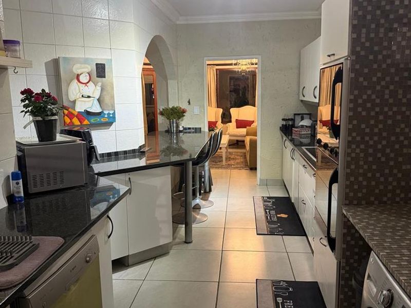 A functional kitchen featuring granite countertops, built-in cabinetry, and a breakfast bar, with an open archway leading into the adjacent living area.