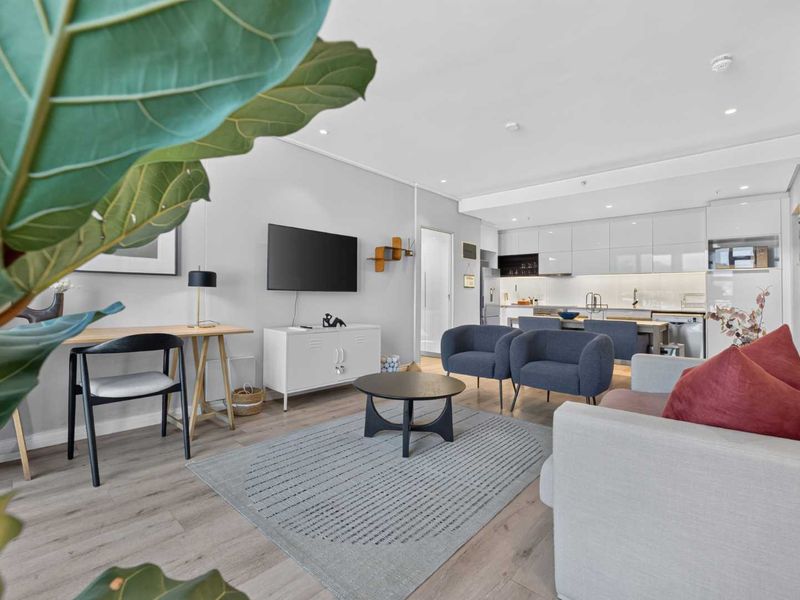 Modern open-plan living area featuring laminate flooring, recessed lighting, and a sleek, contemporary kitchen with integrated appliances.