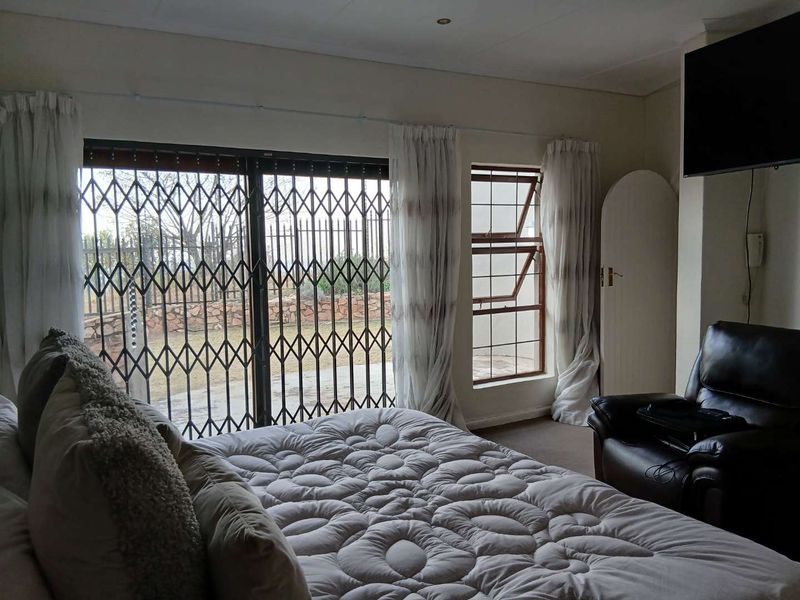 A bedroom featuring a sliding security gate leading to the exterior, a top-hung window, and built-in cupboard storage.