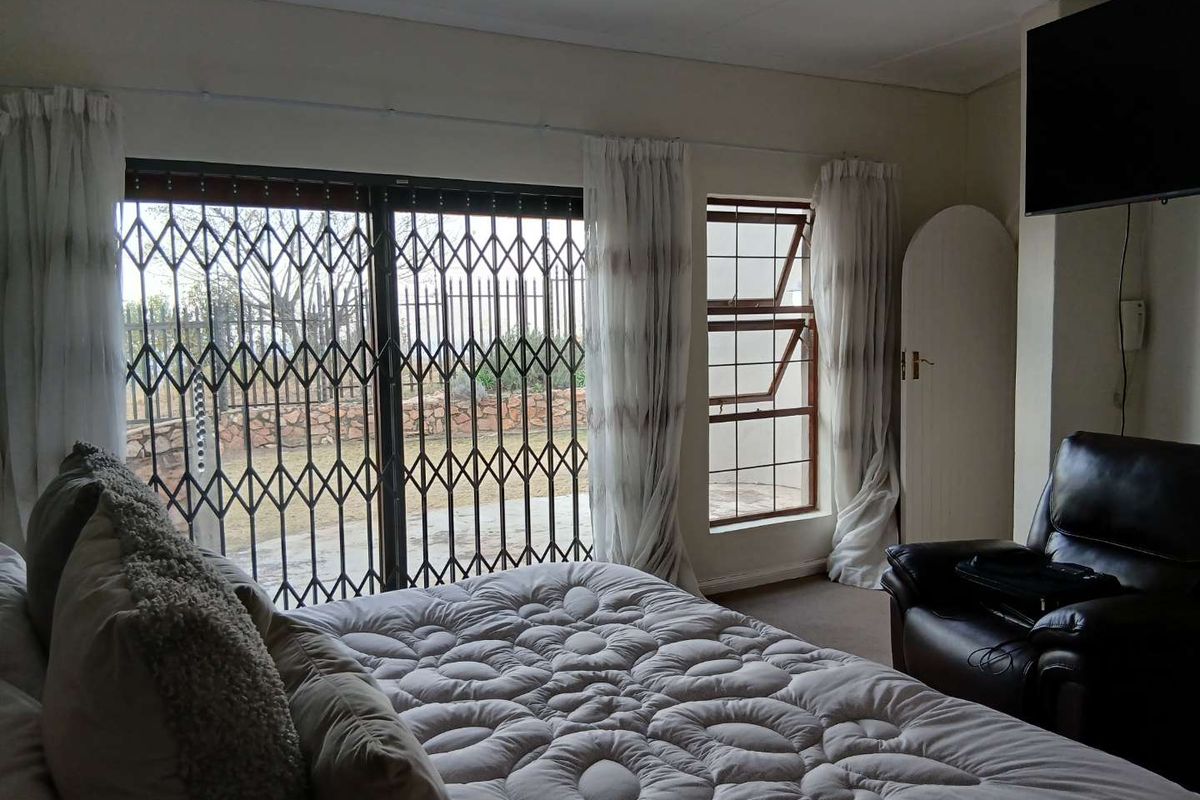 A bedroom featuring a sliding security gate leading to the exterior, a top-hung window, and built-in cupboard storage.