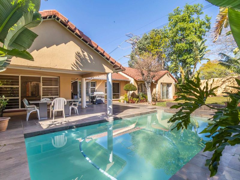 A well-maintained outdoor area featuring a swimming pool and a spacious covered patio, ideal for outdoor entertaining and relaxation.