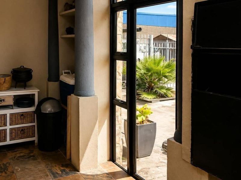 Covered patio area featuring a built-in braai, tiled flooring, and large glass doors opening to an outdoor space.