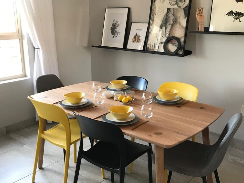 A bright dining area featuring neutral tiled flooring and modern floating wall shelves, providing a clean and functional space for meals.