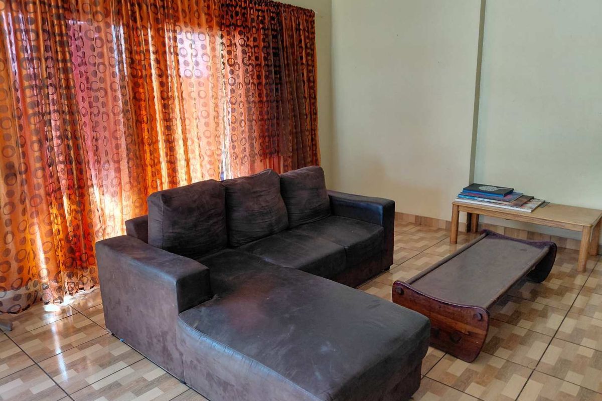 A living room featuring tiled flooring and large window coverage with curtain tracks.