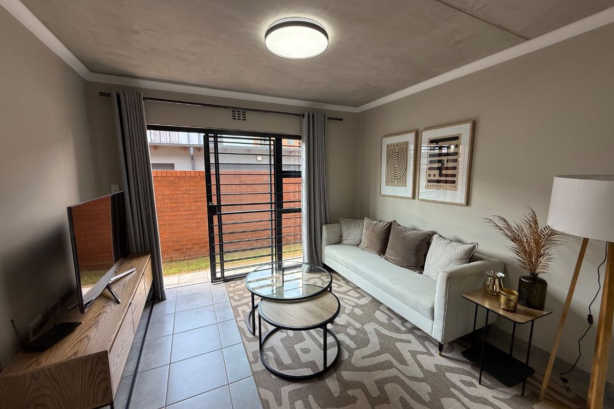 A well-maintained living room featuring tiled floors, an exposed concrete ceiling, and a sliding glass door providing access to the outdoor area.
