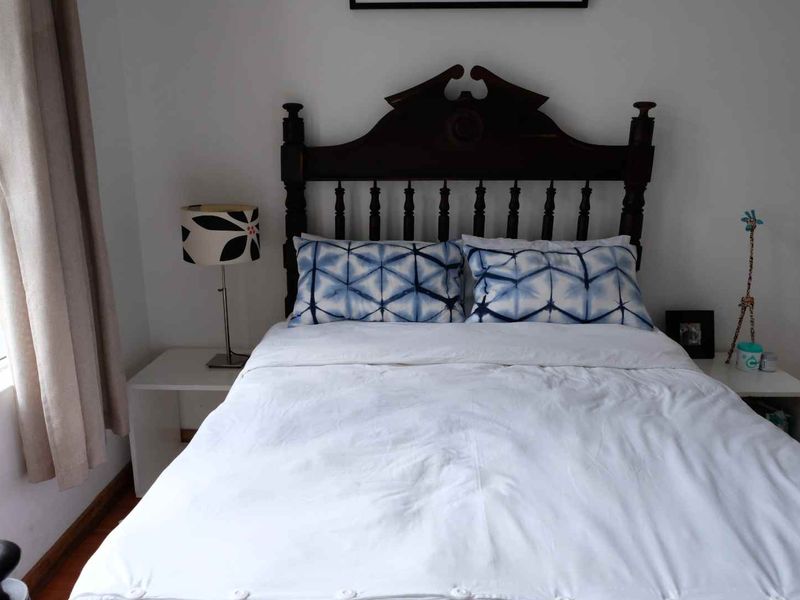 A cozy bedroom featuring a classic wooden headboard and neutral wall finishes, providing a comfortable and functional sleeping space.