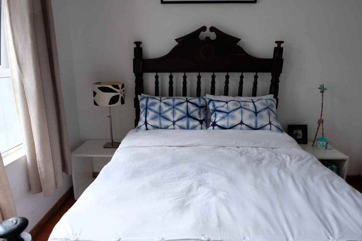 A cozy bedroom featuring a classic wooden headboard and neutral wall finishes, providing a comfortable and functional sleeping space.