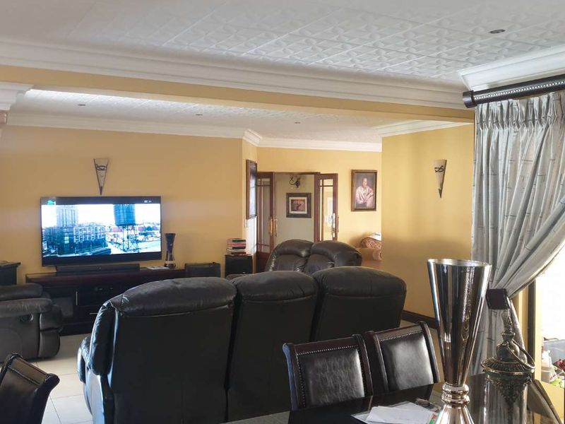 Spacious open-plan living and dining area featuring tiled floors, decorative ceiling tiles, and crown molding, providing a comfortable and functional layout.